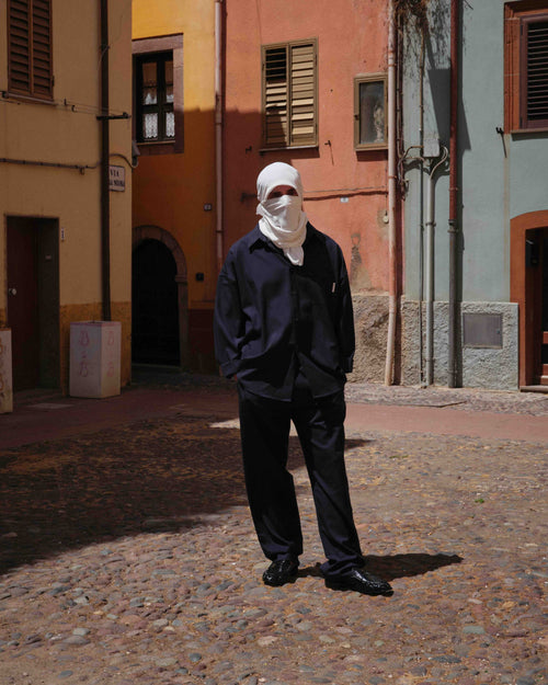 Empty7 habillé en noir dans une rue italienne colorée