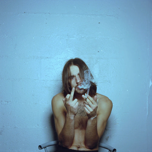 SCH face caméra torse nu fait un doigt d'honneur et fume une clope