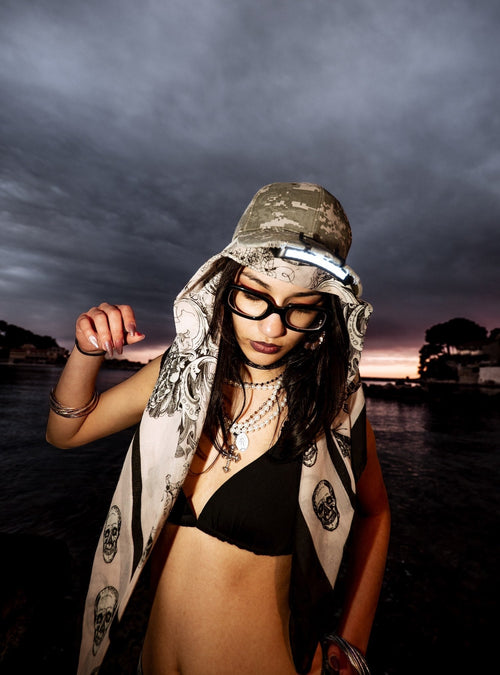 Mandyspie la nuit portant un bob un foulard et des lunettes près d'un lac