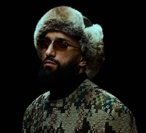 Photo du rappeur Niro en gros plan avec une chapka sur la tête et des lunettes de soleil
