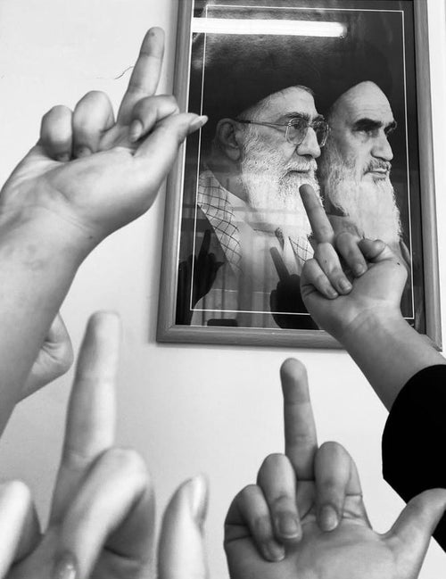 Photographie de doigts d'honneur face à un cadre avec des dirigeants iraniens